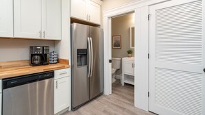 Een moderne keuken met roestvrijstalen apparatuur, witte kastjes en een houten aanrecht.