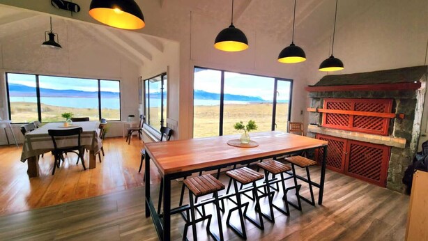 Un'ampia sala da pranzo con tavolo e sedie in legno, ampie finestre con vista sul deserto e lampade a sospensione.
