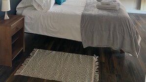 Una camera da letto con un letto, un comodino, una lampada, una finestra e un tappeto decorato.