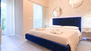 A bedroom with a large bed, a chandelier, a round mirror, and a window with curtains. - Dolomia rosmini (Trento)