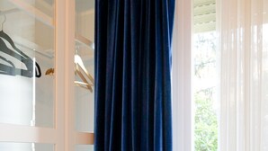 A room with a large window, a white door, and a blue curtain. - Dolomia rosmini (Trento)
