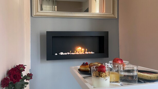 A modern room with a fireplace, a mirror, and a tray with food and drinks. - Dolomia rosmini (Trento)