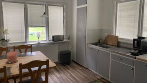 Een kleine keuken met een eethoek, voorzien van een ingebouwde magnetron, spoelbak en opbergkasten.