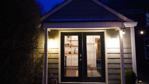 Une petite maison de plain-pied, avec une porte d’entrée sombre et une cuisine visible à travers la porte vitrée.