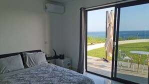 Une chambre avec un grand lit, une table de chevet et une fenêtre donnant sur l’océan.