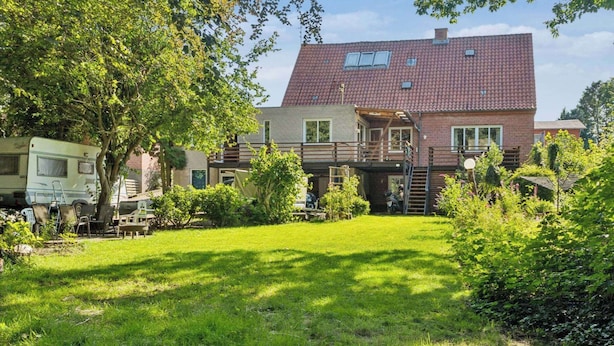 Ein zweistöckiges Haus mit rotem Ziegeldach, einer Veranda und einem gepflegten Rasen.