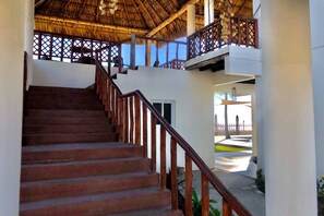 Stairs lead to a thatched-roof upper level with a balcony offering views of the surroundings.