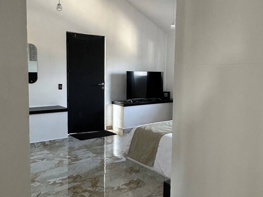Une chambre moderne équipée d’un lit, d’un téléviseur à écran plat et d’un grand miroir.