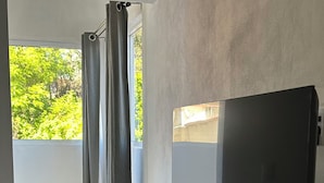 Un salon moderne avec un téléviseur à écran plat, une télécommande et une paire de ciseaux posés sur un sol en marbre.
