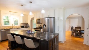 Una cocina moderna con una isla central, electrodomésticos de acero inoxidable e iluminación colgante.
