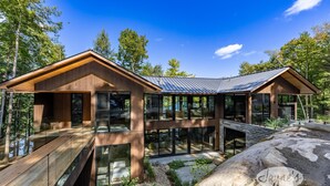 Una cabaña moderna de madera con grandes ventanales, una terraza de madera y un entorno forestal natural.
