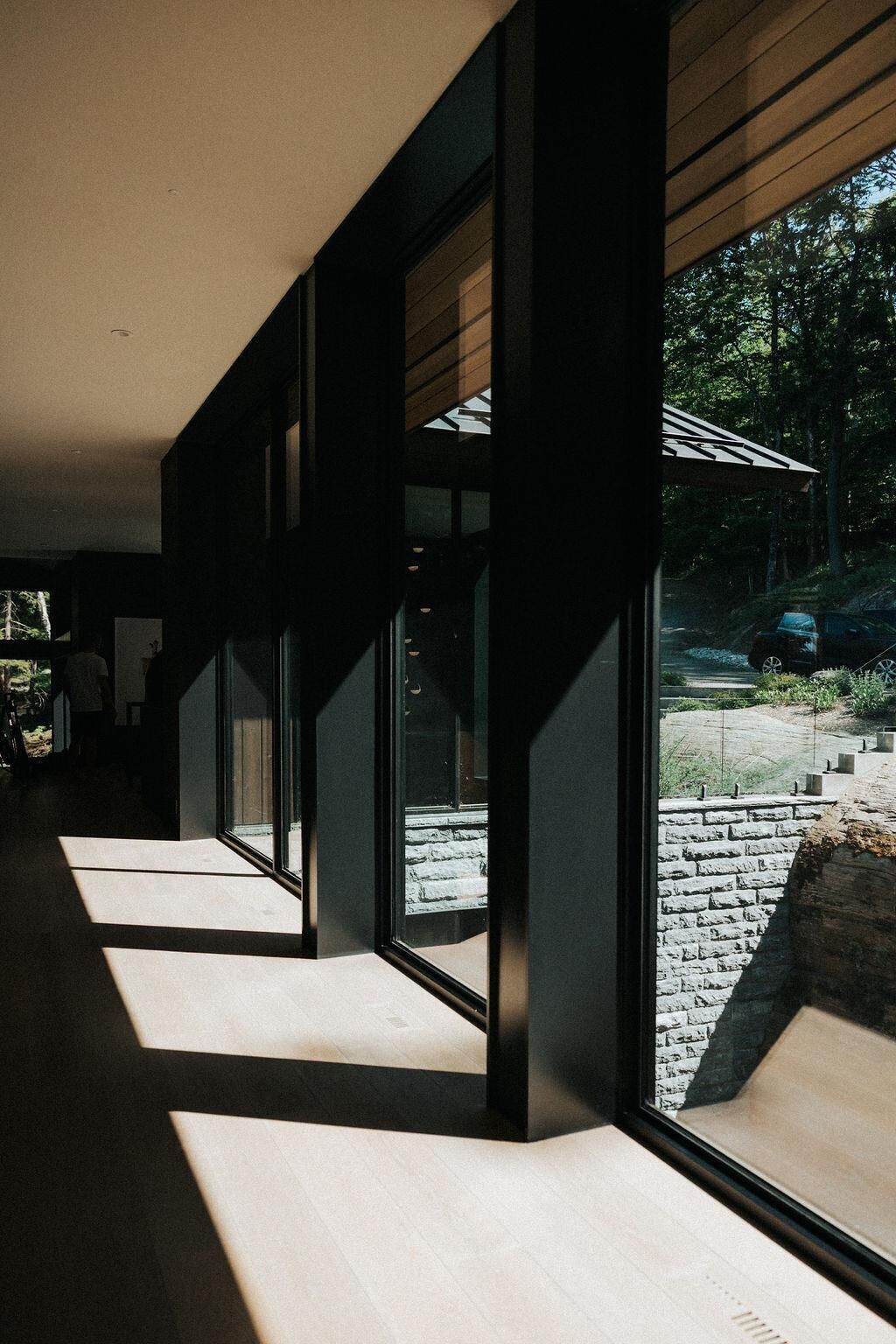A corridor with large windows and a view of a stone pathway and greenery outside.