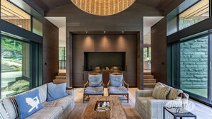 Una sala de estar moderna con chimenea, dos sillones, un sofá y una mesa de centro.