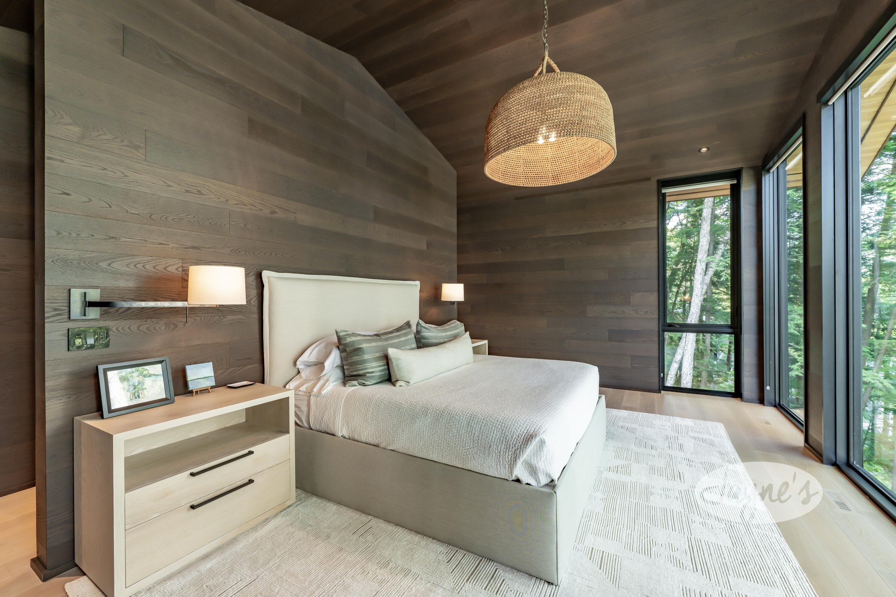Une chambre moderne avec un grand lit, des tables de chevet et une vue sur l’extérieur.