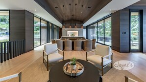 Un interior moderno con una zona de estar central, ventanas amplias y una cocina al fondo.