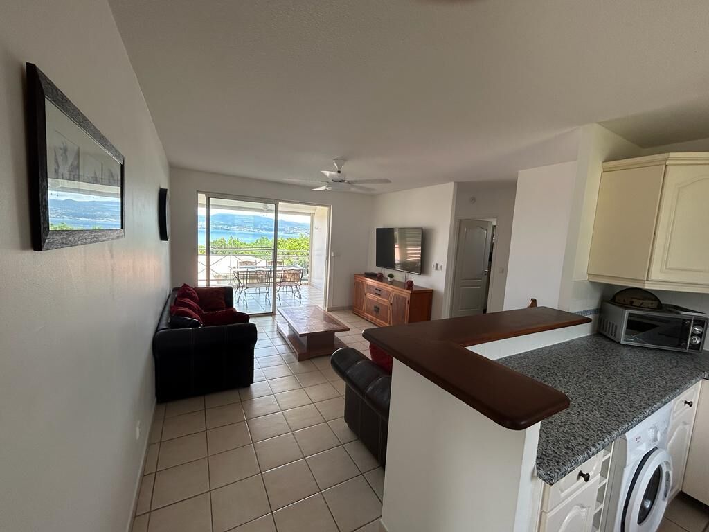 A spacious living area with a sliding glass door leading to a balcony, a kitchen with a built-in oven and microwave, and a small seating area with a sofa and a coffee table.