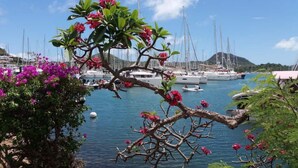 A marina with boats docked, surrounded by lush greenery and flowering plants. - T3 vue mer sur les Caraïbes (Les Trois-Îlets)