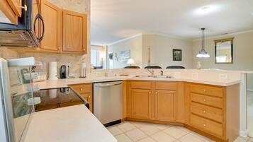 A kitchen with wooden cabinets, a dishwasher, a countertop with a coffee maker, and a sink.