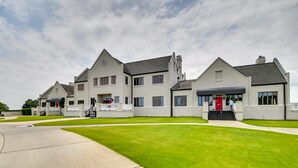 A large, modern building with multiple entry points, a well-maintained lawn, and a clear sky. - Myrtle Beach Condo w/ Community Perks (Myrtle Beach)