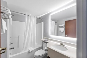 A modern bathroom with a bathtub, toilet, and sink, featuring a large mirror and towel rack.