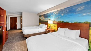 Quarto de hotel com duas camas, cabeceira de madeira, mesa de cabeceira e um grande mural com paisagem na parede.