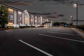 A hotel with a row of rooms, a parking lot, and a sign for Clarion Painting. - Clarion Pointe Starkville near University (Starkville)