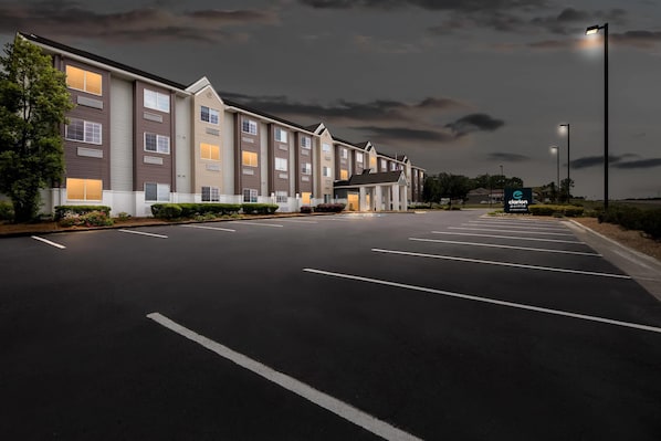 A hotel with a row of rooms, a parking lot, and a sign for Clarion Painting.
