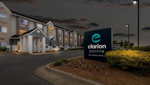 Um hotel com uma placa indicando 'clarion pointe by choice hotels', apresentando um edifício moderno com várias janelas e uma entrada bem iluminada.