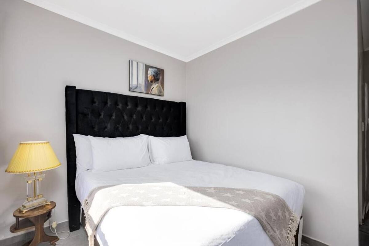 Ein Schlafzimmer mit einem großen Bett, einem Nachttisch mit Lampe und einem Gemälde an der Wand.