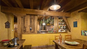 A rustic wooden interior with a dining table, chairs, and a kitchen area visible through a window. - Agroturismo Mari Cruz (Arce)