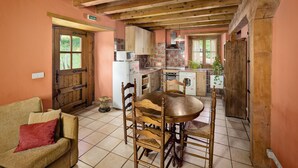 A cozy kitchen with wooden beams, a dining table with chairs, a sofa, and a door labeled "SALIDA". - Agroturismo Mari Cruz (Arce)