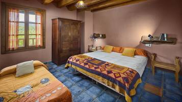 A bedroom with a large bed, a wooden wardrobe, a nightstand, and a window with curtains.