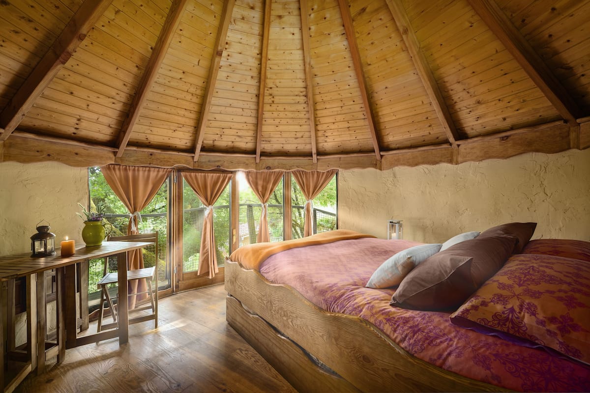 A rustic wooden room with a bed, a table, and a chair.