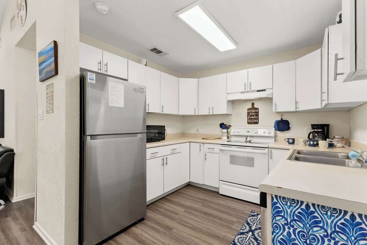 A kitchen with white cabinets, a stainless steel refrigerator, a stove, and a microwave.