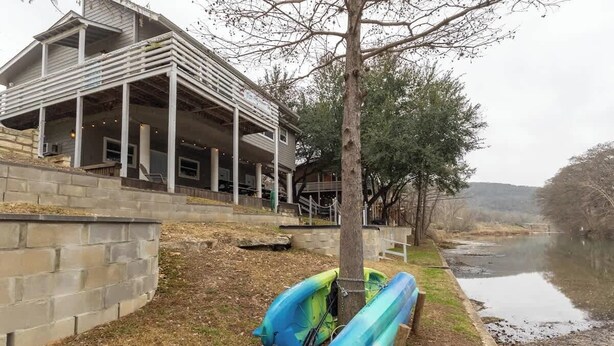 Un bâtiment doté d’un porche couvert, avec une rivière en arrière-plan.