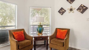 Een kamer met twee fauteuils, een bijzettafeltje, een lamp en wanddecoratie.