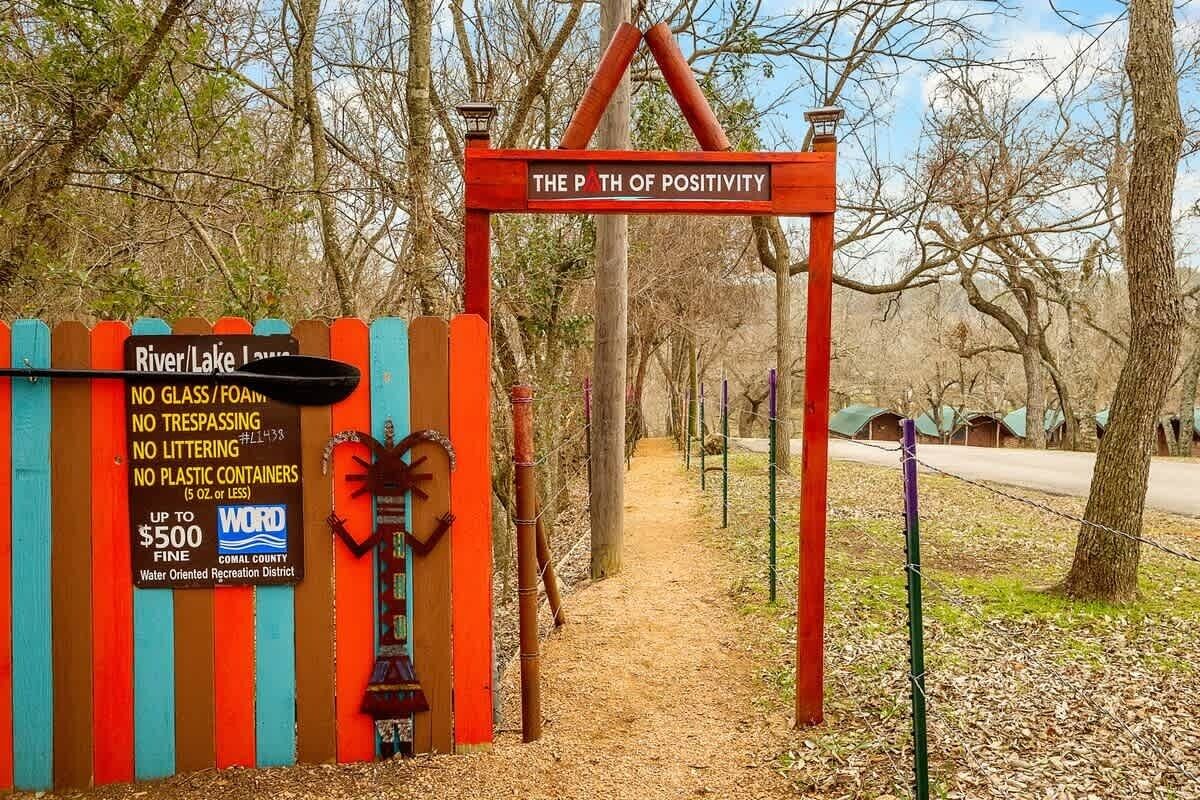 Schild für 'The Path of Positivity' mit Holzzaun und einem Verbotsschild.