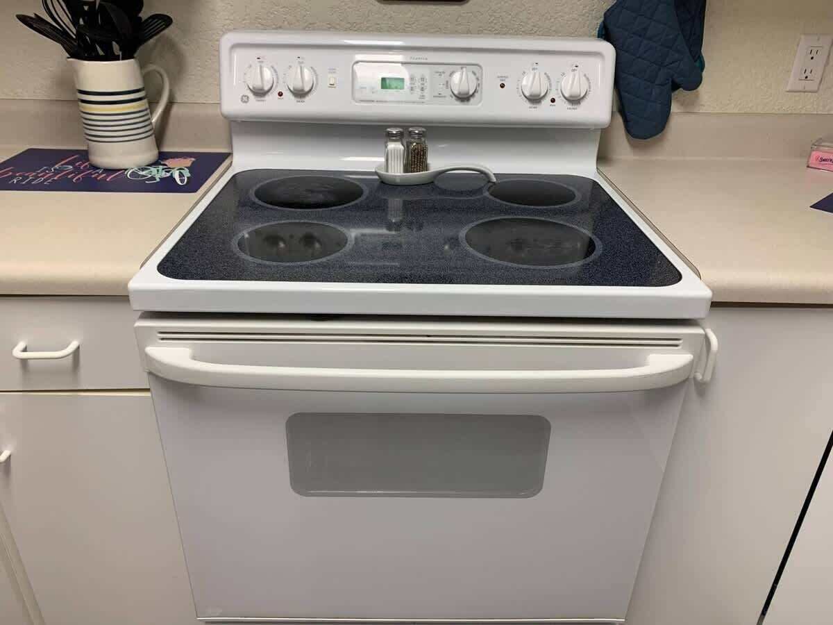 A white stove with four burners and a digital control panel.