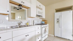 Une cuisine moderne avec des meubles blancs, une cuisinière, un four à micro-ondes et un réfrigérateur.