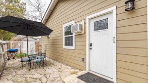 Une maison avec une terrasse en pierre, une porte blanche et un appareil de climatisation.