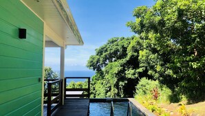 Une terrasse en bois avec une piscine, entourée d’une végétation luxuriante et offrant une vue sur l’océan.