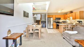 Un espace de vie compact comprenant un coin repas, une kitchenette et une chambre en mezzanine.