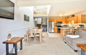 Un espace de vie compact comprenant un coin repas, une kitchenette et une chambre en mezzanine.