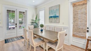 Un coin repas avec une table en bois et six chaises, une plante en pot et un tableau accroché au mur.