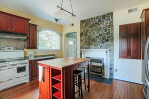 A kitchen with a stone fireplace, wooden cabinets, and a large island.