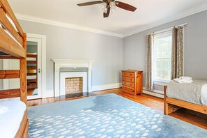 A bedroom with a bunk bed, a fireplace, a dresser, and a window with curtains. - Clonmel Acres: Historic Estate with Hot Tub & Pond (Afton)