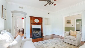 Un salon spacieux doté d’une cheminée, d’un ventilateur de plafond et d’un grand tapis.