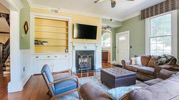 A living room with a fireplace, a television, and a large window.