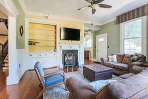 A living room with a fireplace, a television, and a large window.