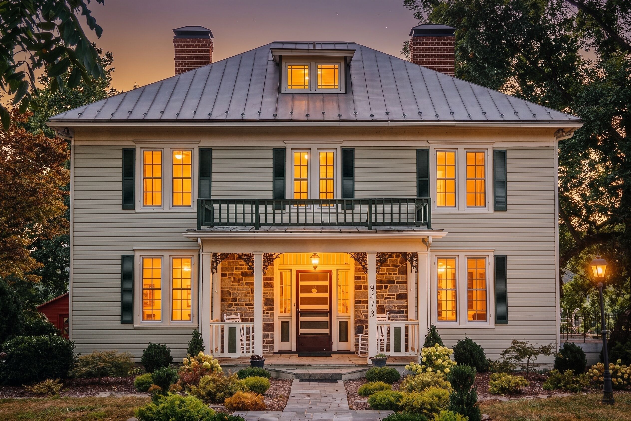 A two-story house with a balcony, a front porch with chairs, and a stone facade.